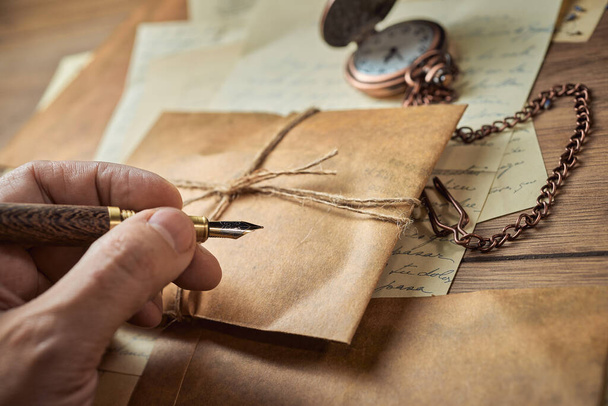 Винтажные письменные принадлежности на деревянном столе, старые часы, бумаги, письма, конверты и ножницы - Фото, изображение