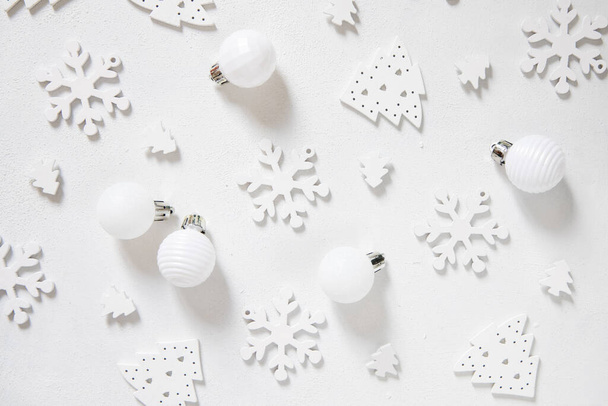 Λευκά χριστουγεννιάτικα στολίδια και νιφάδες χιονιού σε λευκό τραπέζι πάνω όψη. Μονόχρωμη χειμερινή σύνθεση με διακόσμηση διακοπών - Φωτογραφία, εικόνα