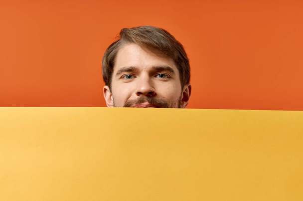 Der bärtige Mann wirbt mit Werbeflächen auf orangefarbenem Hintergrund. Hochwertiges Foto - Foto, Bild