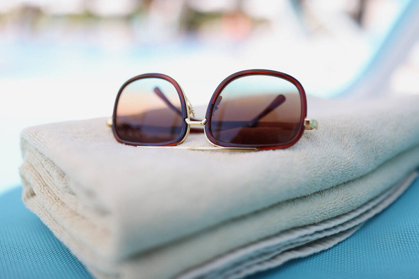 Sunglasses lying on brown cotton towels on lounger closeup - Foto, afbeelding