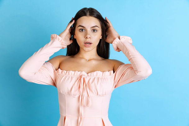 Cropped portrait of young beautiful Caucasian girl with shocked facial expression isolated over blue background - Photo, Image