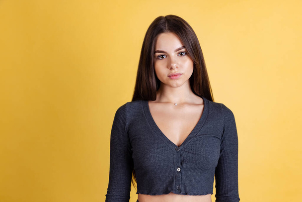 Cropped portrait of young beautiful Caucasian woman looking at camera posing isolated over yellow backgoround - Foto, immagini