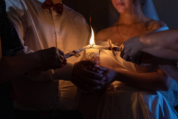 Brûler une bougie d'une cérémonie de mariage dans un restaurant. Une bougie dans les mains des jeunes mariés - Photo, image