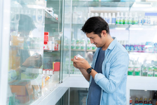 Ázsiai férfi boldogan vásárolt gyógyszereket a gyógyszertárban, orvosi ellátás koncepció. - Fotó, kép