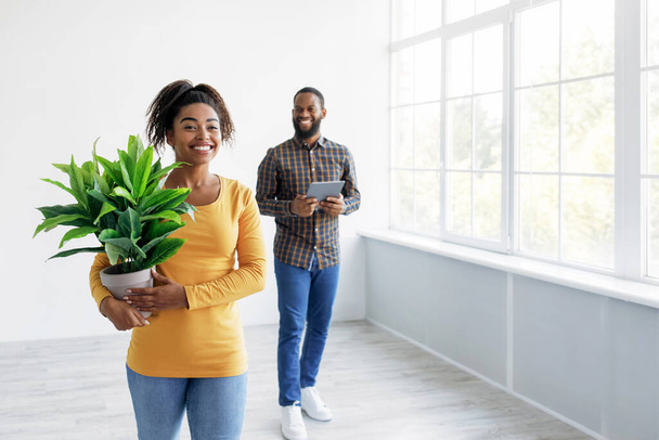 Glückliche junge afrikanisch-amerikanische Eheleute inspizieren das Innere der neuen Wohnung und planen das Design - Foto, Bild