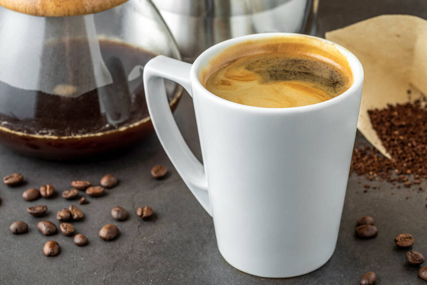 Uma xícara de café e terceira geração despeje sobre o equipamento de fabricação de café no chão de pedra - Foto, Imagem