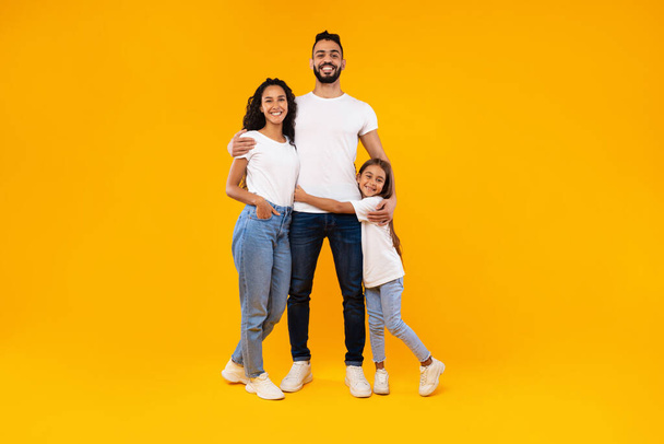 Middle-Eastern Parents And Daughter Embracing Expressing Positive Emotions, Yellow Background - Photo, Image