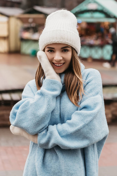 Young pretty smiling woman looking at the camera dressed knitted hat mittens. Cold weather, winter holidays, travel. New Year Christmas fair decorations, Valentines Day concept copy space - Foto, Imagem