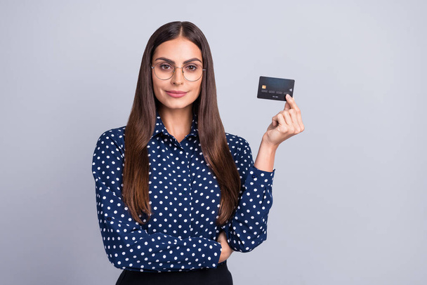 Portrait of attractive cheery smart clever businesswoman holding in hand bank card freelance isolated over grey color background - Foto, imagen