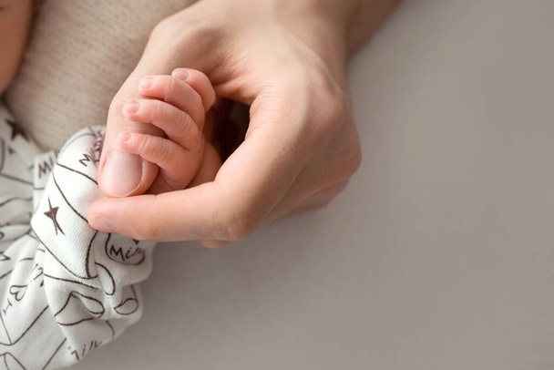 Szczęśliwa mama z miłością trzyma palce noworodka  - Zdjęcie, obraz