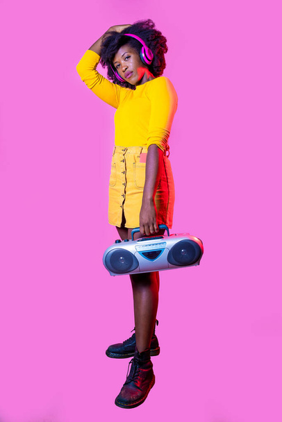 Young black woman posing isolated background confident holding vintage boombox - Valokuva, kuva