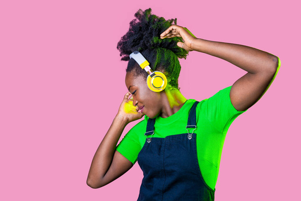 Joven cabello rizado mujer negra aislada bailando escuchando música con auriculares inalámbricos - Foto, Imagen