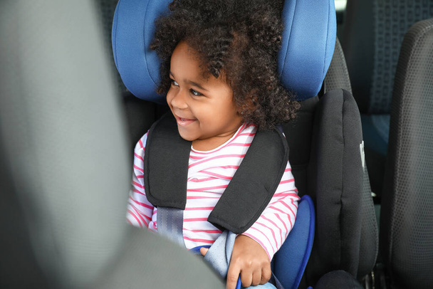 Pequena menina afro-americana presa no assento de segurança do carro - Foto, Imagem