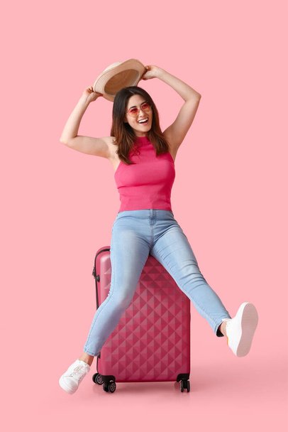 Νεαρή γυναίκα με βαλίτσα στο φόντο χρώμα - Φωτογραφία, εικόνα