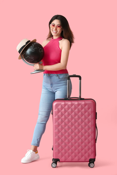 Молодая женщина с чемоданом и глобусом на цветном фоне - Фото, изображение