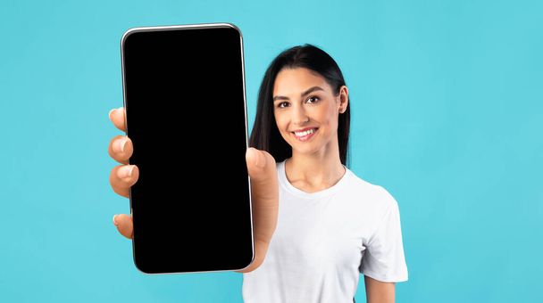 Mobilní aplikace Mockup. Krásná mladá žena ukazuje velký smartphone s černou obrazovkou - Fotografie, Obrázek