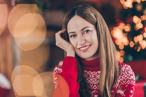 Photo of dreamy pretty young woman dressed red sweater arm cheek hand cheekbone celebrating new year smiling indoors room home house - Photo, image