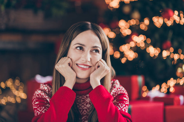 Photo of adorable pretty young woman dressed red sweater arms cheeks celebrating new year smiling indoors room home house - Φωτογραφία, εικόνα