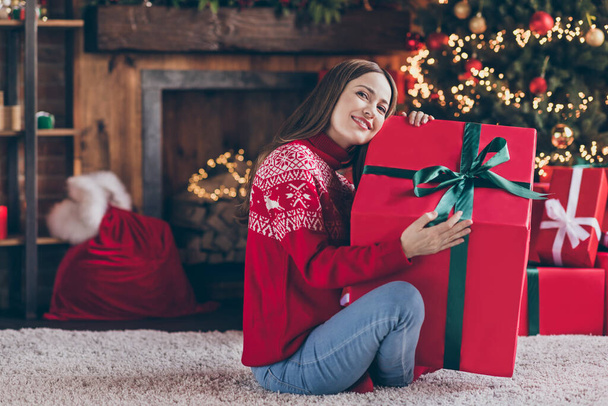 Photo of charming cute mature lady wear red pullover smiling hugging christmas big present box indoors house home room - Foto, Imagen