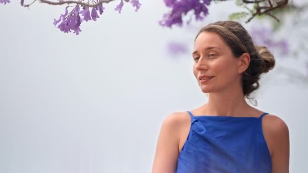 Femme caucasienne en robe bleue posant, arbre aux fleurs roses à Barcelone, Espagne - Séquence, vidéo