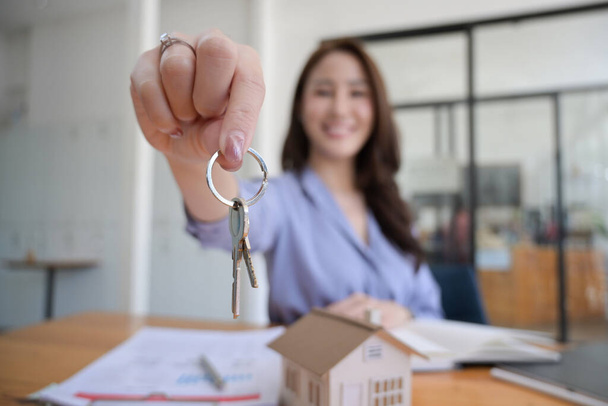 Großaufnahme lächelnde Immobilienagentur mit Hausschlüssel. Immobilieninvestitionskonzept. - Foto, Bild
