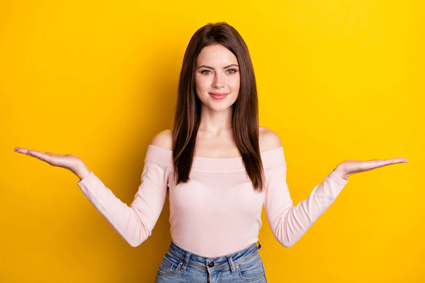 Photo of young happy beautiful smiling woman hold hands in balance advertisement isolated on yellow color background - Fotó, kép