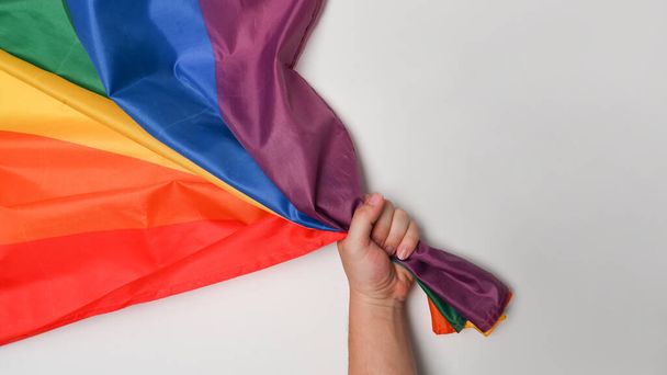 Man χέρι κρατώντας LGBT σημαία υπερηφάνειας σε λευκό φόντο. - Φωτογραφία, εικόνα