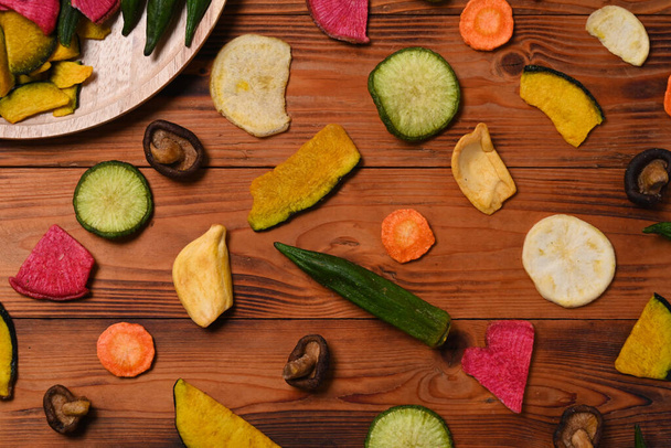 Colorful mixed dried vegetables chips on wooden background. - Photo, Image