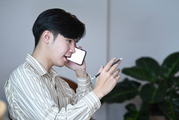 Handsome businessman sitting in comfortable workplace and talking on mobile phone. - Photo, image