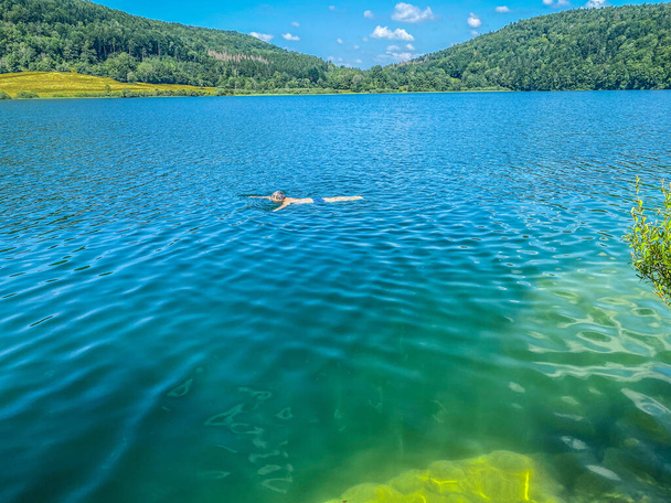Una persona irreconocible nada en el lago Narlay, Le Frasnois, Bourgogne-Franche-Comte, Jura - Foto, Imagen