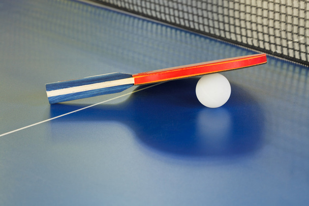 весло, теннисный мяч на синем столе для пинг-понга
 - Фото, изображение