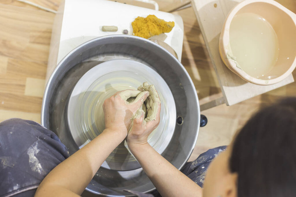 女性陶芸家の手で陶器の車輪の上に粘土を形成します。創造的な手作りの工芸品。陶芸スタジオ. - 写真・画像