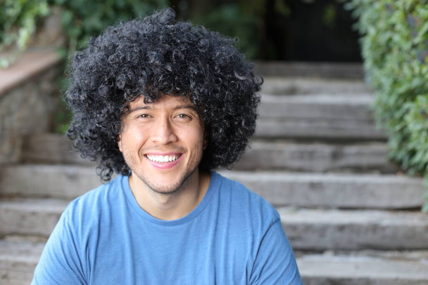 close-up portrait of handsome young man with curly black hair outdoors - Photo, Image