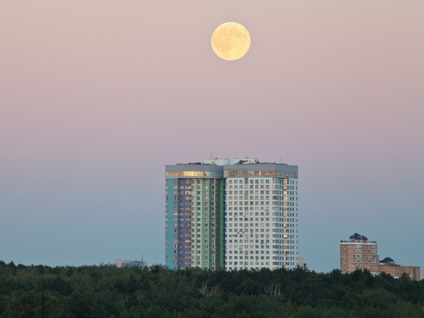 luna llena en el cielo nocturno sobre casas urbanas
 - Foto, Imagen