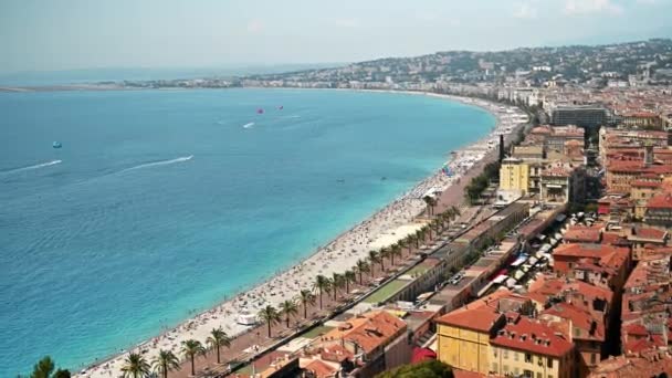 Vista de la costa de Azur en Niza, Francia. Múltiples descansando en la playa personas, edificios, agua azul del mar Mediterráneo - Imágenes, Vídeo