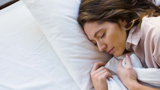 Top view egy nő egyenesíti a takarót, mosolyog álmában, és édesen alszik. - Felvétel, videó