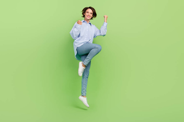 Full body photo of cheerful young joyful nice happy woman jump up winner cool isolated on green color background - Valokuva, kuva