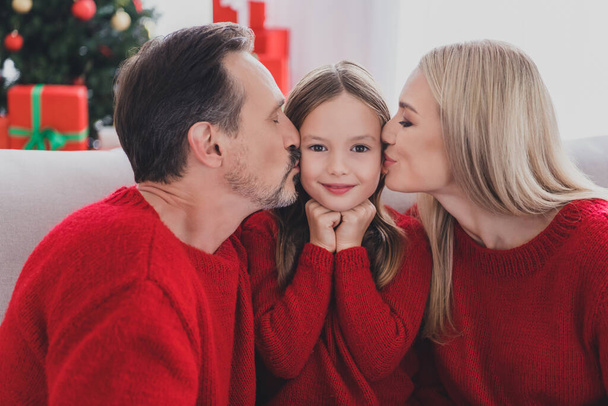 Portrait of attractive cheerful family wife husband parenthood sitting on cozy sofa mom dad kissing schoolgirl december at home indoors - Fotografie, Obrázek