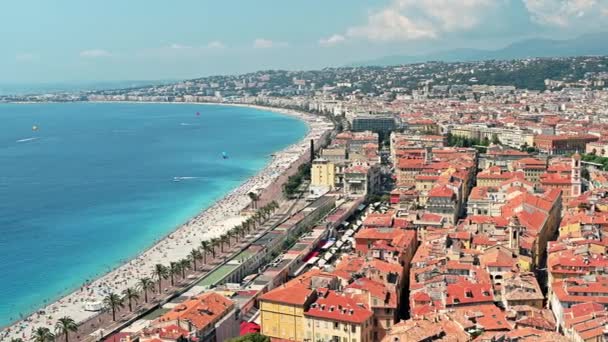 Vista de la costa de Azur en Niza, Francia. Múltiples descansando en la playa personas, edificios, agua azul del mar Mediterráneo - Metraje, vídeo