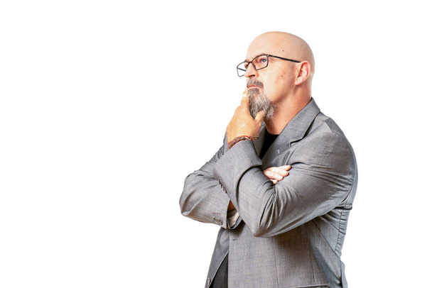 hombre atractivo calvo con traje gris de negocios haciendo posturas de asombro, foto sobre fondo blanco - Φωτογραφία, εικόνα