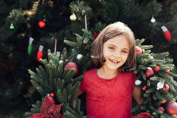Merry Christmas. Portrait of happy funny child girls in Santa hat with Christmas wreath. Happy Holidays. Fairy Magic. Happy kid enjoying holiday. Christmas in July - Zdjęcie, obraz