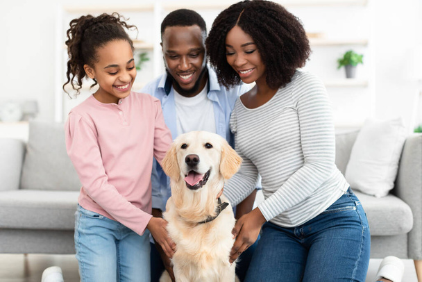 Joven familia negra abrazándose con el perro posando en casa - Foto, Imagen