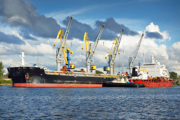 Rakományhajók a kikötői terminálon. Daruk a háttérben. Balti-tenger. Bunkering, üzemanyag és energiatermelés, ellátás, technológia, logisztika, szolgáltatás, ipar, üzlet, kereskedelem - Fotó, kép