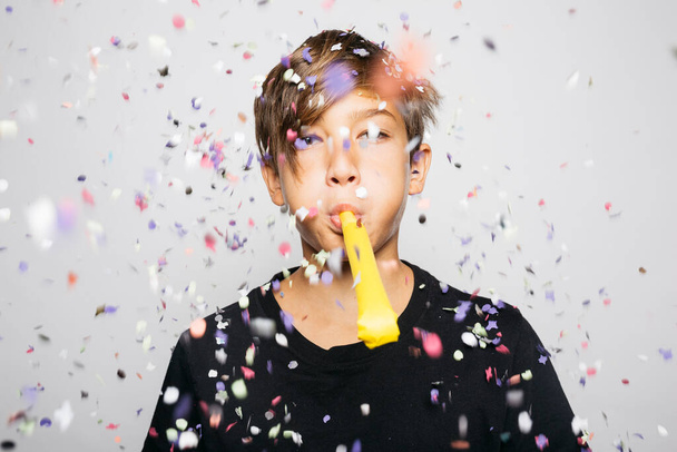 Portrait of a twelve years old boy throwing confetti to the air - Photo, Image