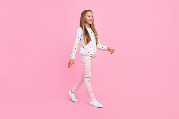 Foto de perfil de positivo agradable despreocupado pequeña dama caminar usar pantalones de camisa punteada calzado aislado de color rosa fondo - Foto, Imagen