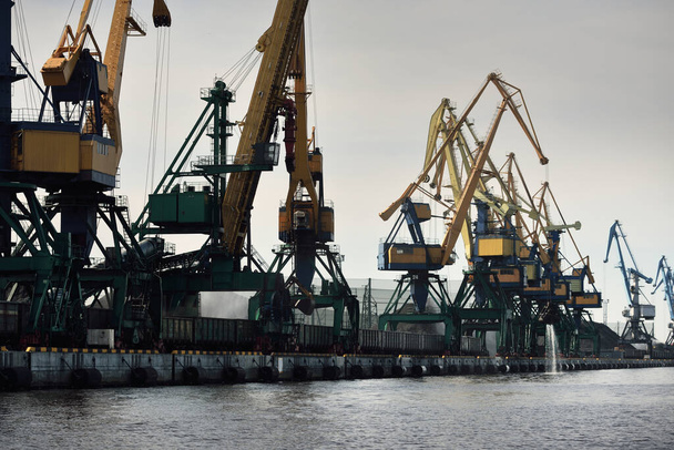 Moderna terminal de carbón en Riga, Letonia. Grúas en primer plano. Mar Báltico. Transporte de mercancías, logística, comunicaciones globales, economía, negocios, industria, suministro, equipos especiales. Paisaje urbano - Foto, imagen