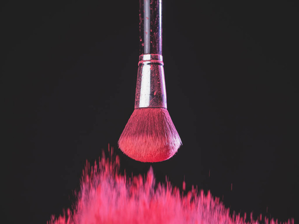 Make-up brush with pink powder explosion on black background - Photo, Image