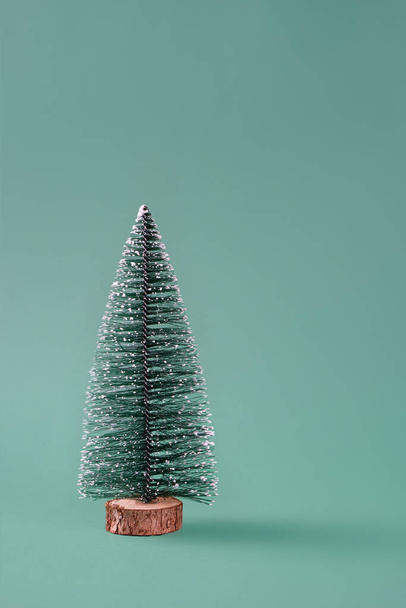 Beautiful fake miniature Christmas tree not decorated over a green background. Small Christmas tree. Copy space, front view. - Foto, Bild