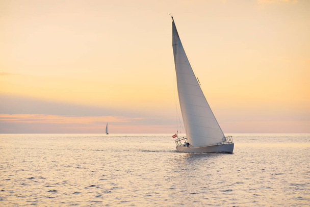 Sloop bianco barca truccata vela nel Mar Baltico al tramonto. Cielo limpido dopo la tempesta, luce dorata del sole. Trasporti, viaggi, crociera, sport, ricreazione, attività ricreative, corsa, regata - Foto, immagini