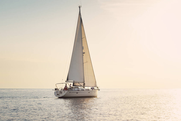 Sloop blanc gréé yacht naviguant dans la mer Baltique au coucher du soleil. Ciel clair après la tempête, soleil doré. Transport, voyage, croisière, sport, loisirs, loisirs, course, régate - Photo, image